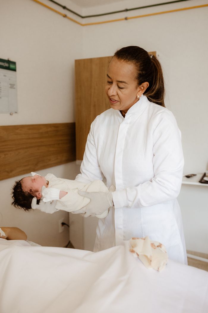 A caring obstetrician holding a newborn baby in a hospital room, symbolizing healthcare and motherhood.