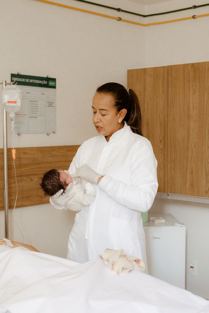 Healthcare professional holding a newborn in a hospital setting, showcasing care and compassion.