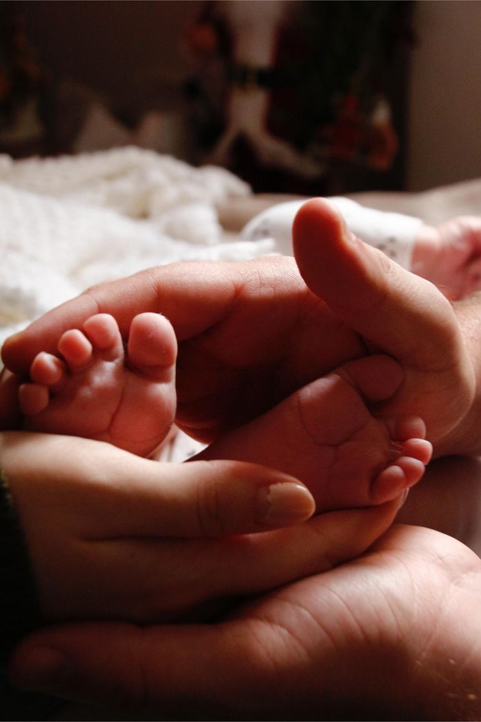 Small baby feet cradled gently by adult hands, symbolizing love and care.