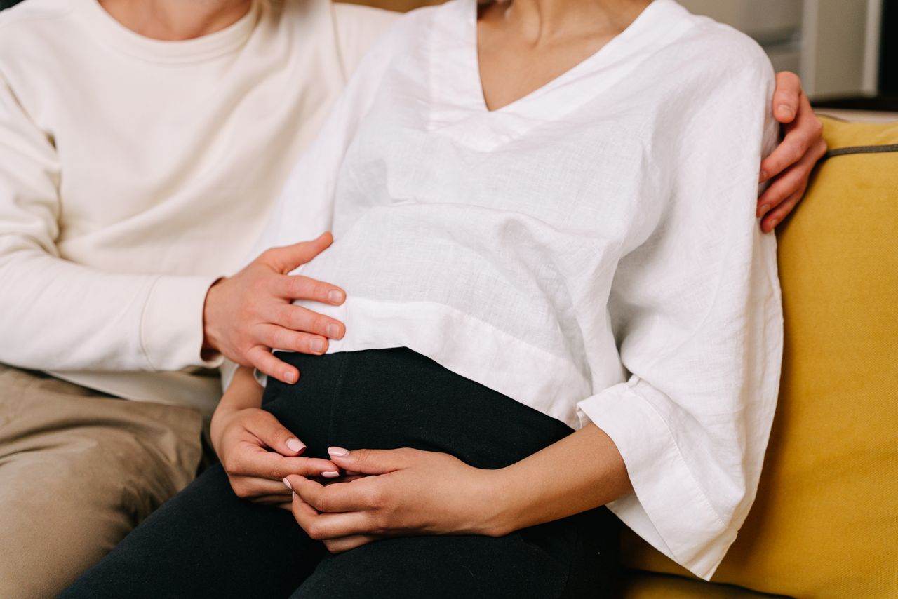 Close-up of couple embracing and touching a pregnant belly, symbolizing family and love.